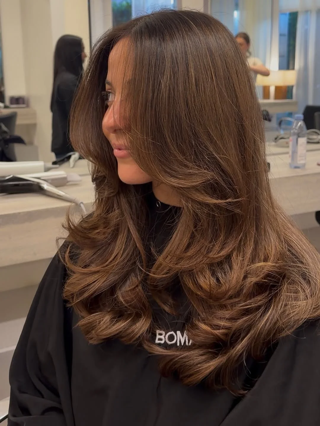 flattering summer haircut for round face 2026 Polished mid-length layers that balance volume and structure