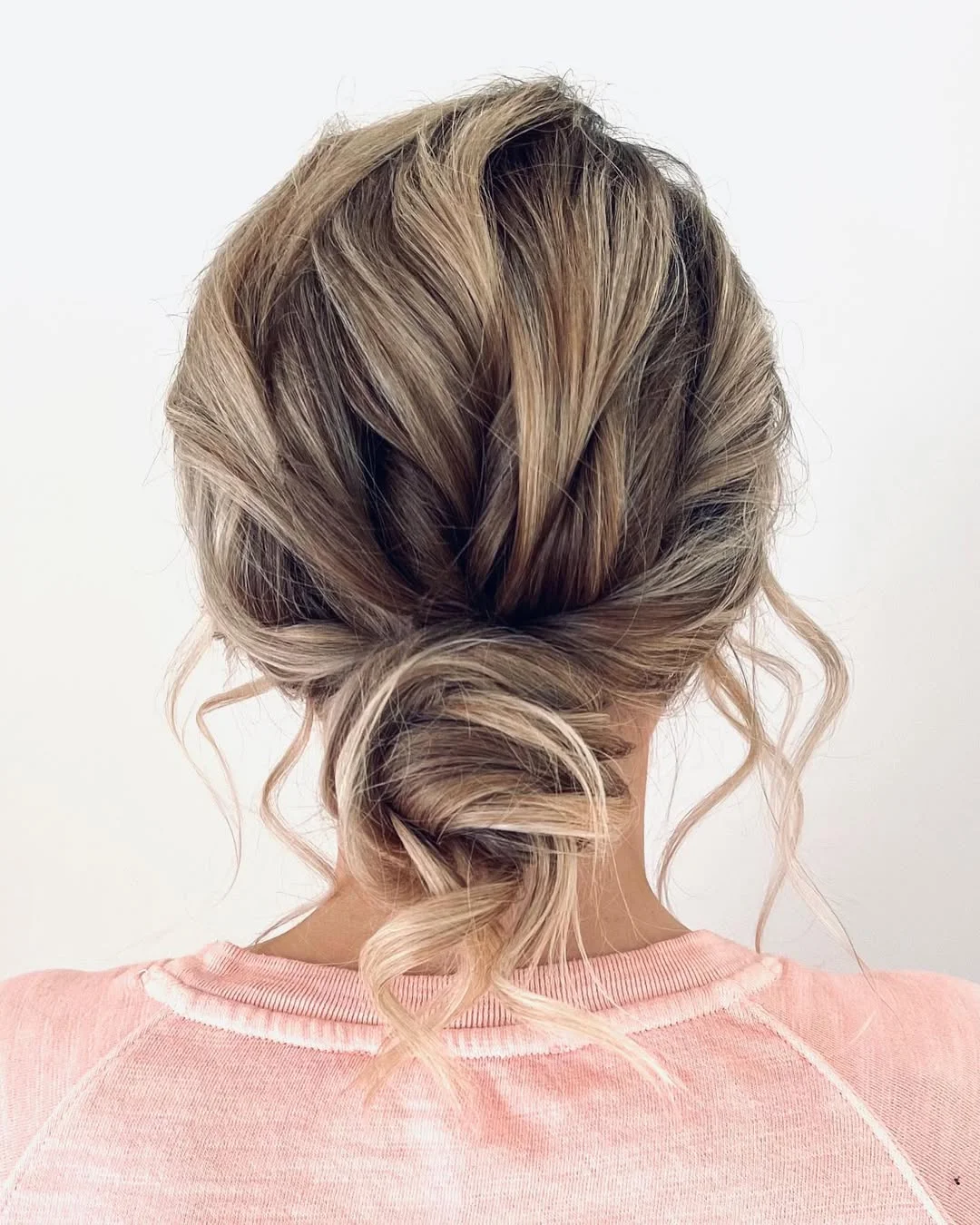 messy summer bun hairstyles 2026 Twisted Low Bun With Face Framing Waves
