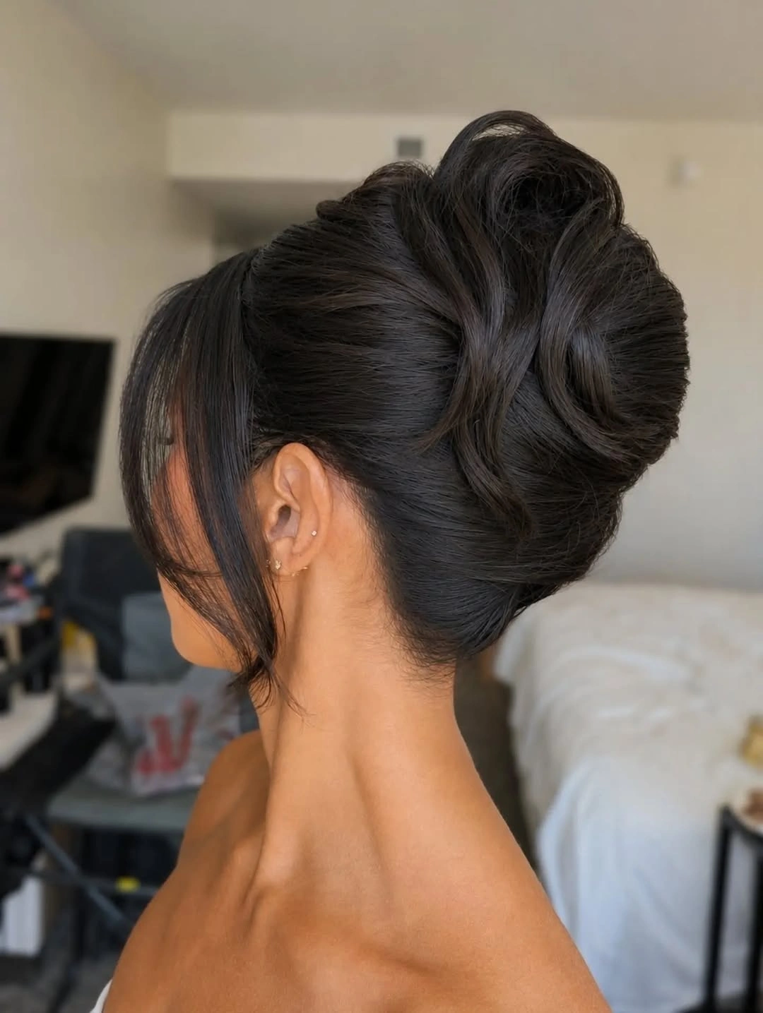fall hairstyles for wedding guests 2026 Polished Sculpted Bun With Soft Curtain Pieces