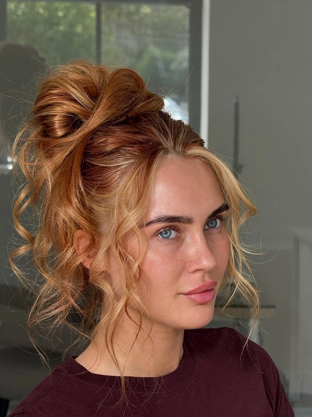 fall hairstyles for wedding guests 2026 Voluminous Curly High Bun With Warm Autumn Tones