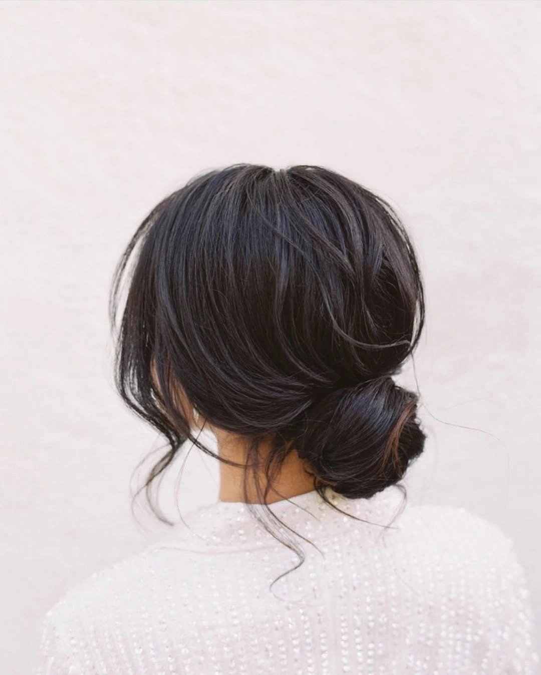 middle parting hairstyles Low Polished Bun With Loose Face Framing Pieces