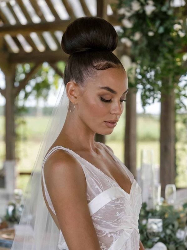 Sleek Dark Brown High Bun With Wispy Bangs — Classy Bridal Hairstyles
