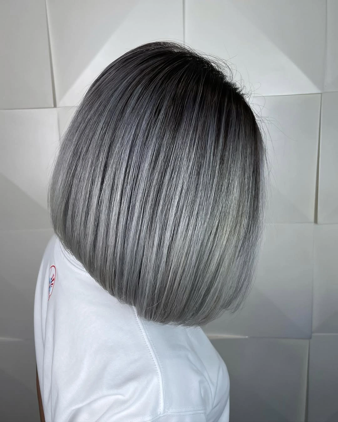 Short rounded silver gray bob with dark graphite roots and smooth ends