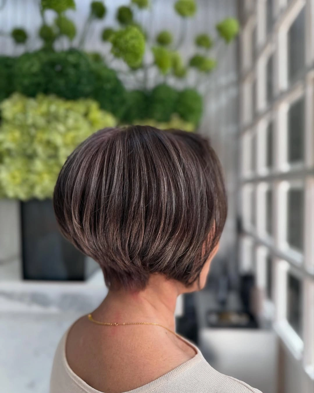 Short rounded brown pixie bob with subtle smoky mauve streaks and tapered nape