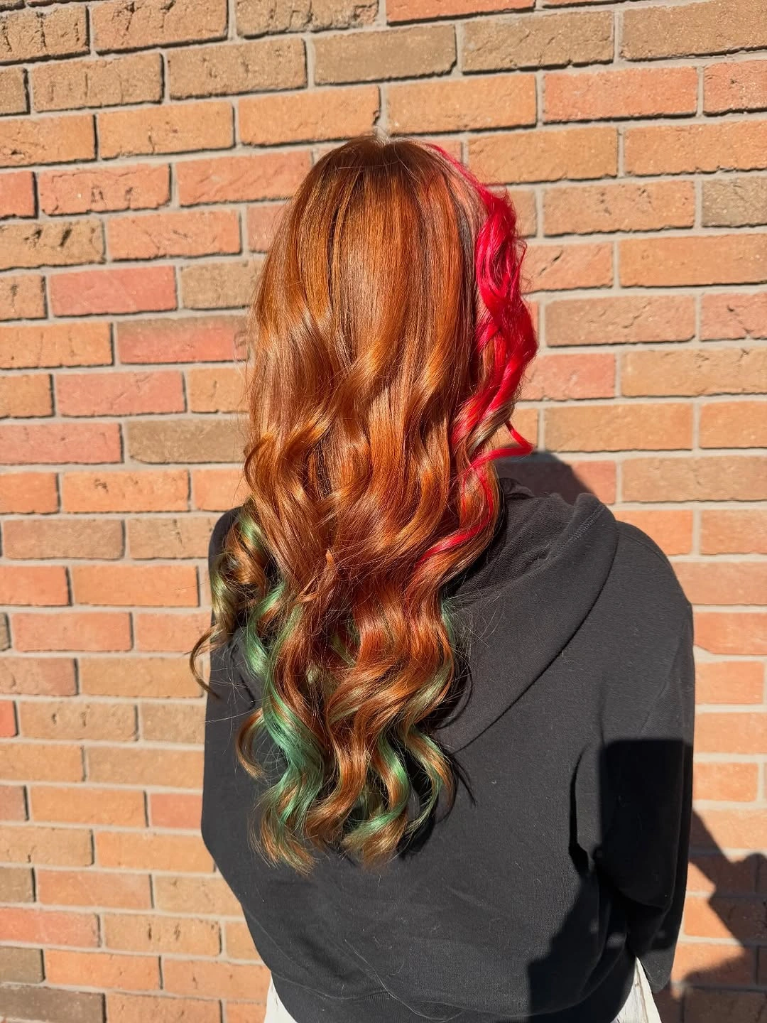Long copper auburn waves with vivid red side strands and green lower curls