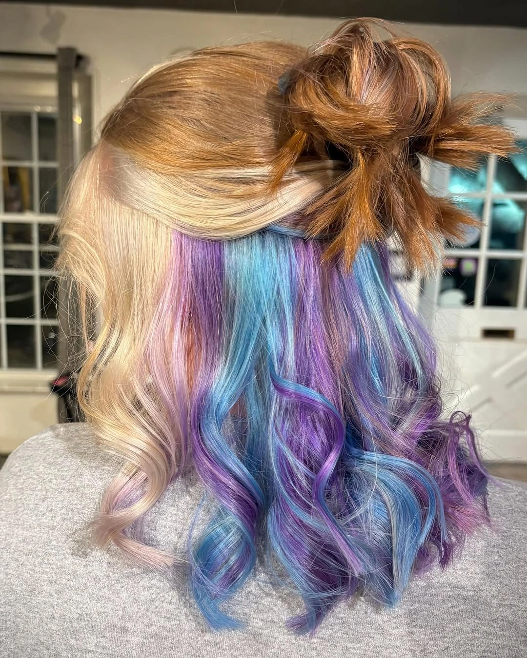 Golden blonde half up hairstyle revealing cyan blue violet and lilac curls underneath