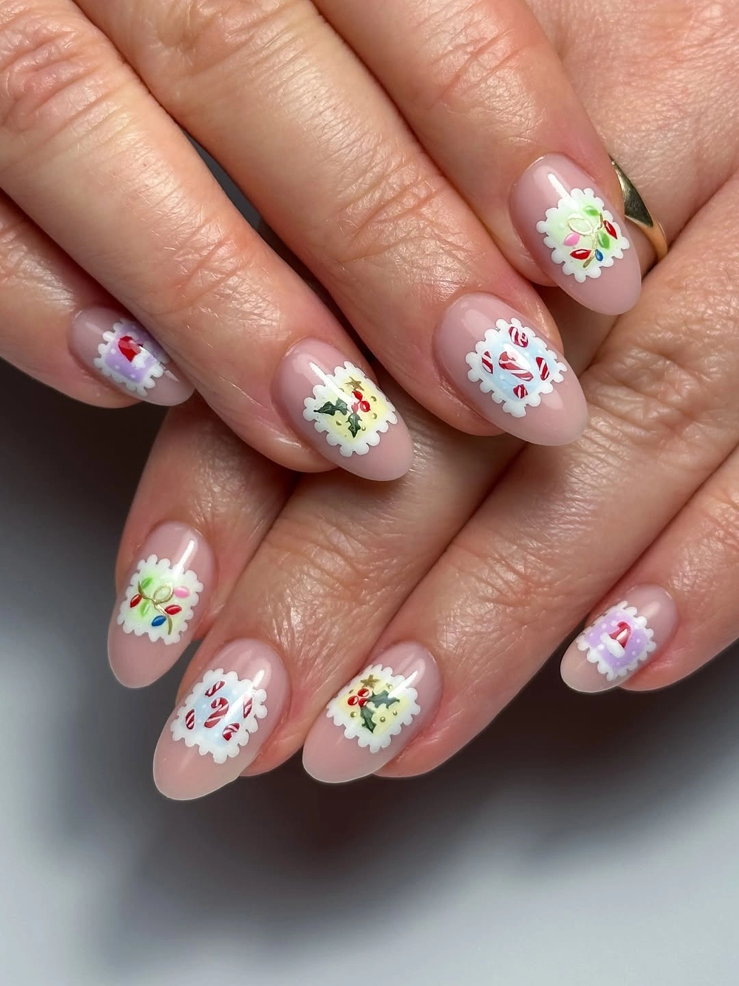 Short rounded pink nails with white scalloped circles and colorful miniature decorations