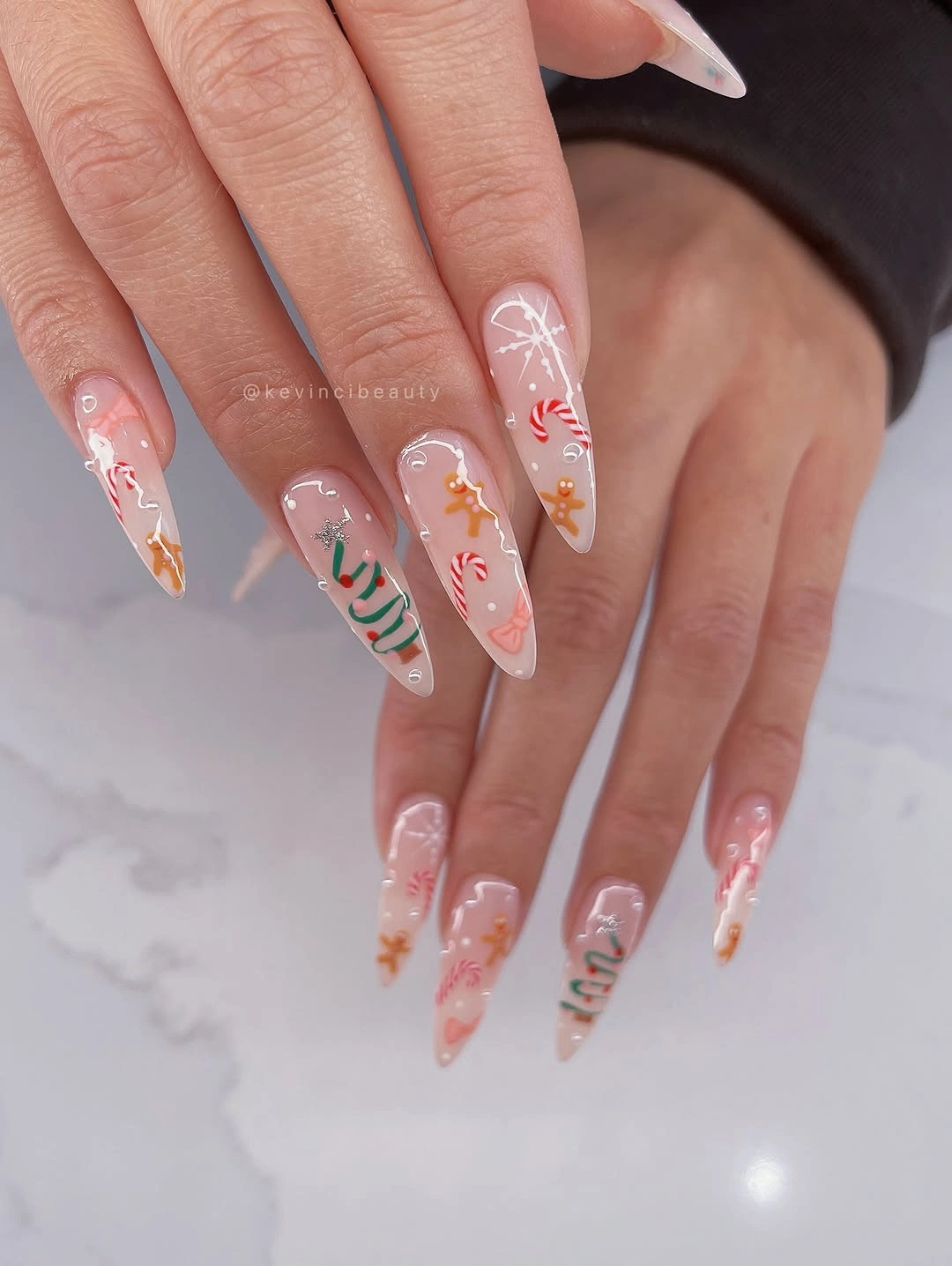 Long square pink nails with gingerbread figures candy stripes and festive illustrations