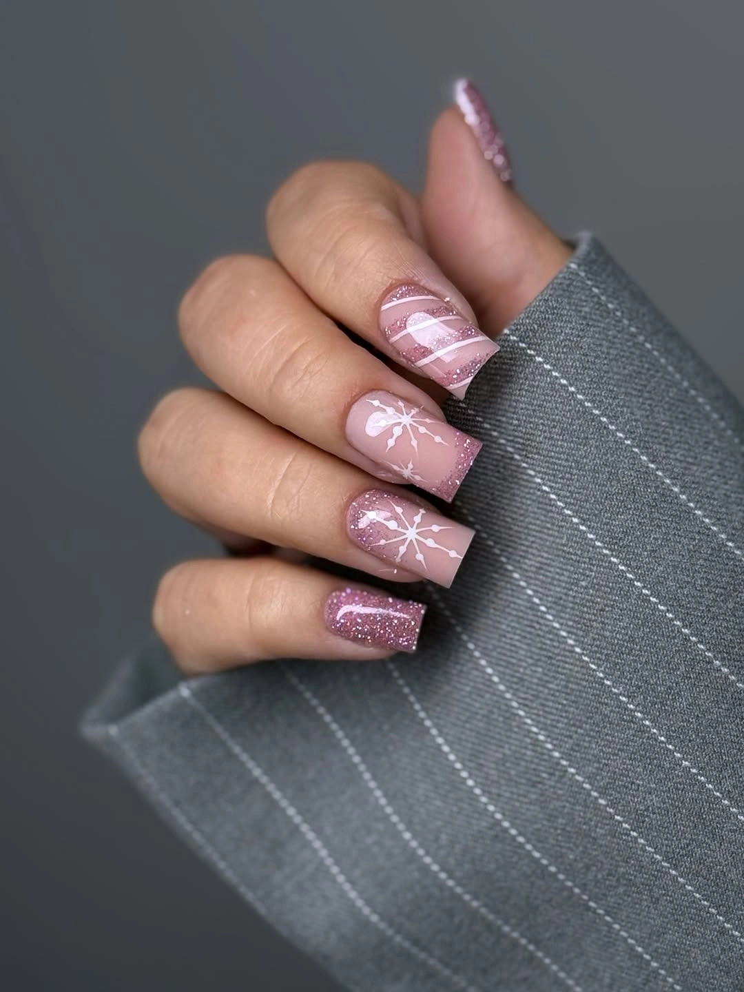 Short square pink nails with white snowflakes and mauve glitter accents