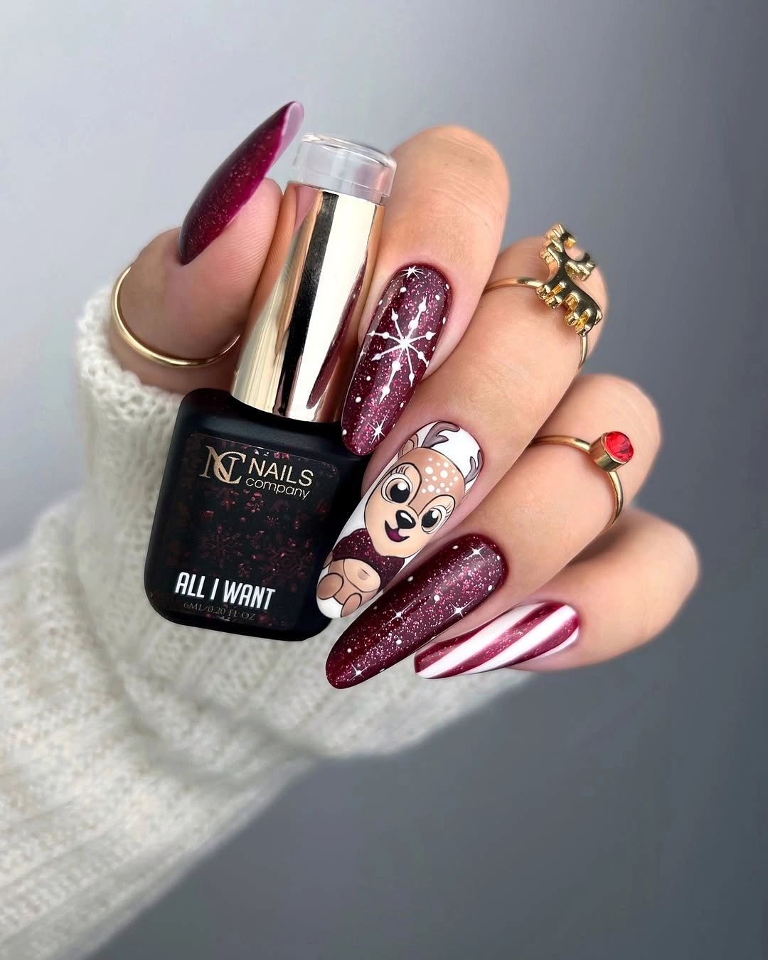 Pointed burgundy glitter nails with reindeer illustration and candy cane stripes